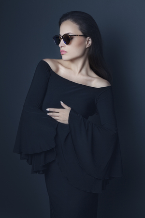 elegant young woman wearing black evening dress and sunglassesの写真素材