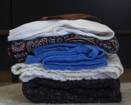 a stack of warm clothes is folded near the dresser