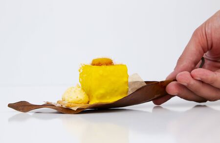 beautiful stylish new yellow cake on an autumn leaf on white backgroundの写真素材
