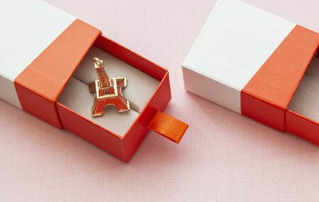 in the open gift box lies the eiffel tower on pink background