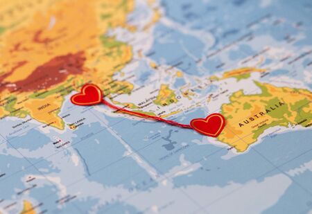 two red hearts on a world map connected by red threadの写真素材