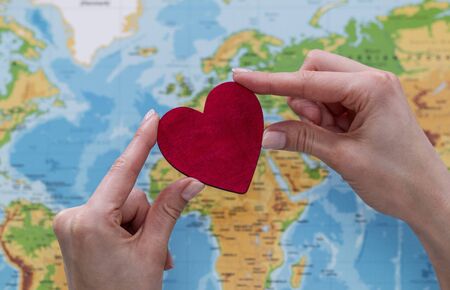 man holds red heart on world map backgroundの写真素材