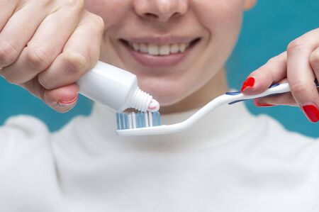 beautiful girl squeezes out toothpaste against the background of a smile