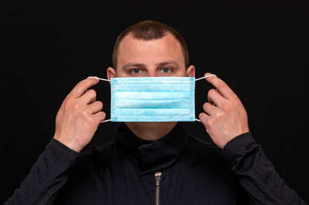 man puts on a medical mask on his face, instructions on how to wear a mask