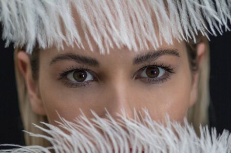beautiful girl posing with a large white feather on a dark backgroundの写真素材