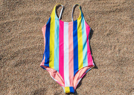 a multicolored swimsuit lies on the sand on the beachの写真素材