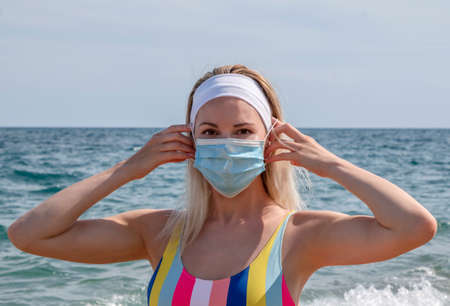 a beautiful girl in a medical mask on the beachの写真素材