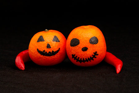 the orange mandarines painted like a halloween pumpkin, happy halloween citrus, red pepperの写真素材
