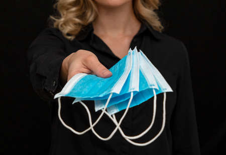 girl offers some new clean medical masks on a dark backgroundの写真素材