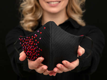 girl demonstrates a beautiful stylish medical mask with precious stones, handmade for a holiday