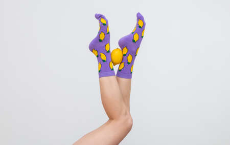 a female legs in colorful socks with lemons isolated on white backgroundの写真素材