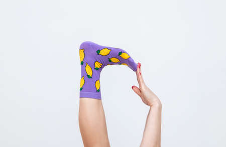 female legs in colorful socks with lemons isolated on white backgroundの写真素材
