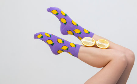 female legs in colorful socks with lemons isolated on white background