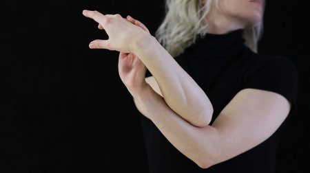 Elegant Female Hands in Graceful Gesture on Black Backgroundのeditorial素材