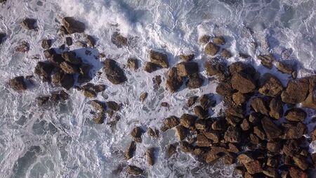 Ocean waves are breaking on a Breakwater at winter sea. Aerial top down view.の写真素材