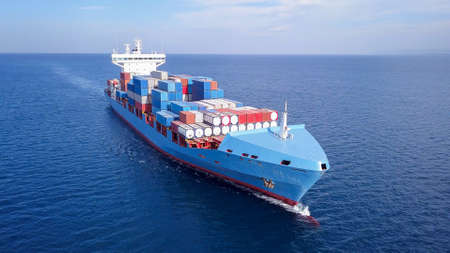 ULCV container ship sails on open water fully loaded with containers and cargo.の写真素材