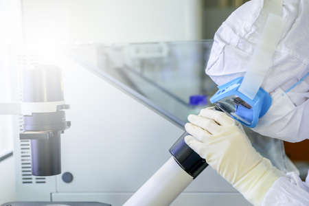 Lab scientists wear protective clothing looking for microscopes while doing medical research in a science laboratory.