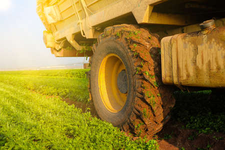 Agriculture concept. Tractor Wheel covered in mud and plowing field in the background.の写真素材