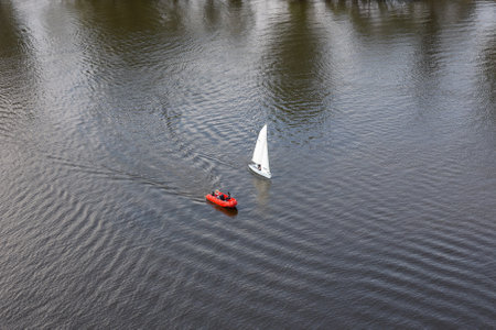 Small sailboat and red motorboat on rippling river water.の写真素材