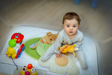 a little baby girl is sitting in an aviary with toysの写真素材