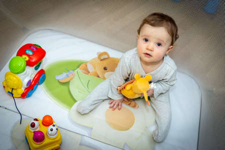a little baby girl is sitting in an aviary with toysの写真素材
