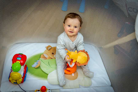 a little baby girl is sitting in an aviary with toysの写真素材