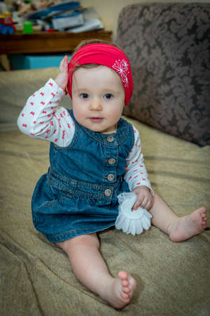 little baby girl in a denim dress on the couchの写真素材