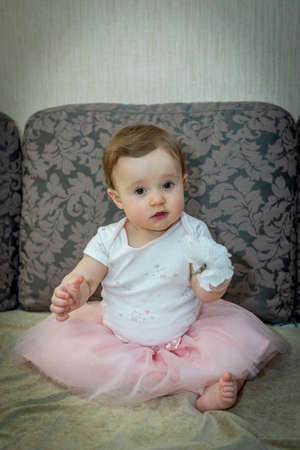 little girl on the couch in a pink skirtの写真素材