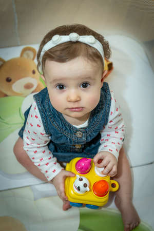 a little baby girl is sitting in an aviary with toysの写真素材