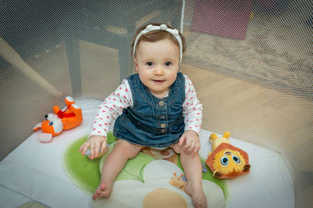 a little baby girl is sitting in an aviary with toysの写真素材