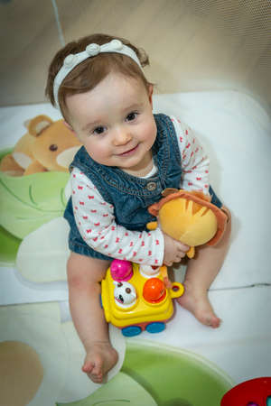 a little baby girl is sitting in an aviary with toysの写真素材
