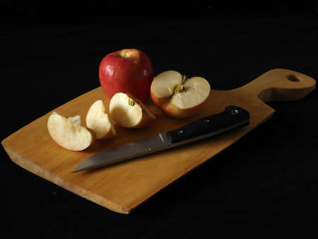 sliced apple with a knife on a cutting board on the tableの写真素材