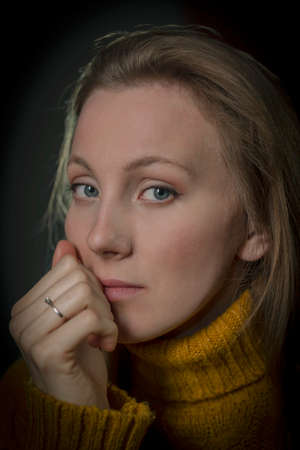 portrait of a young woman in a yellow sweater on a black backgroundの写真素材