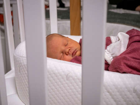 a little newborn baby girl is sleeping in a cribの写真素材