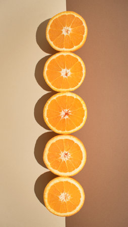 Fresh orange slices on a pastel earthy brown background. Minimalistic fruit flat lay composition, aesthetic arrangement, creative concept.の写真素材