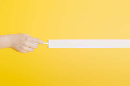 Creative geometric idea with a womans hand holding a white shaving razor. Illuminating bright background, white and yellow concept, modern linear flat lay composition.の写真素材