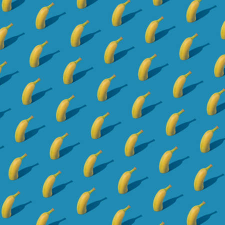 Creative fruit pattern arrangement with halved banana on bright blue background. Minimalistic geometric concept, colorful summer idea.の写真素材