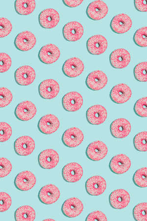 Summer vibes pattern idea with pink donut on bright blue background. Minimalistic geometric arrangement, happy sunny concept. Flat lay composition.の写真素材