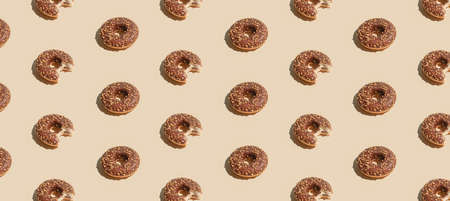 Creative summer vibes concept with fresh brown chocolate doughnuts on pastel bright beige...