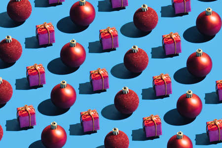 Colorful vivid decoration idea with red baubles against bright blue background. Minimal pattern seamless composition, creative visual New Year and Christmas concept.の写真素材