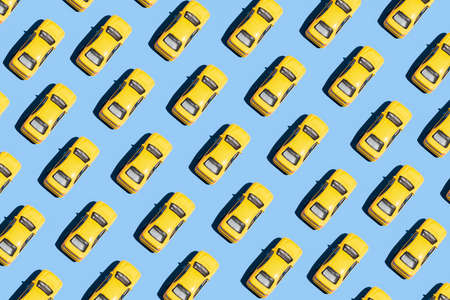 Minimal creative pattern concept with yellow cars on blue background. Aesthetic transportation idea, vivid colors, simple composition.の写真素材