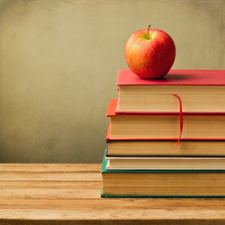 Old books and apple on wooden table over grunge backgroundの写真素材