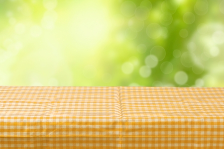 Empty table coved with tablecloth over bokeh garden backgroundの写真素材