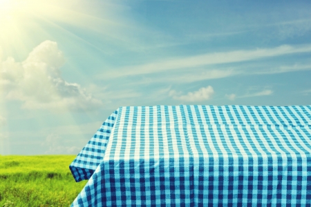 Empty table covered with blue checked tablecloth over beautiful sky. Ready for product montageの写真素材