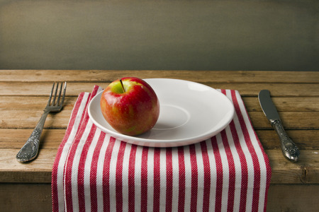 Red apple on white plate, table arrangement.の写真素材