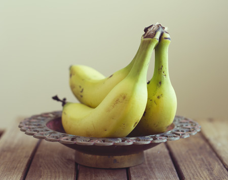 Bananas in vintage bowl on wooden tableの写真素材