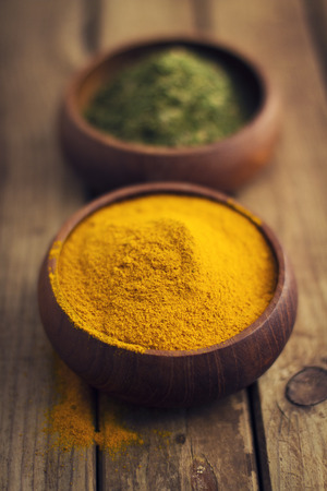 Spices in wooden bowls on wooden tableの写真素材