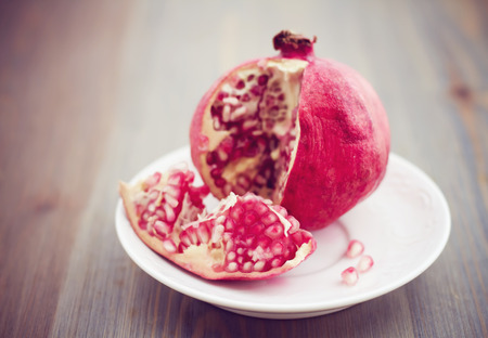 Pomegranate on white plate on wooden tableの写真素材