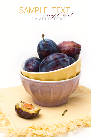 Fresh plumps in colorful bowls on white backgroundの写真素材