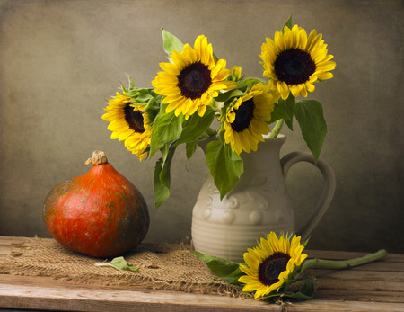 Still life with sunflower bouquet and pumpkin on wooden tableの写真素材